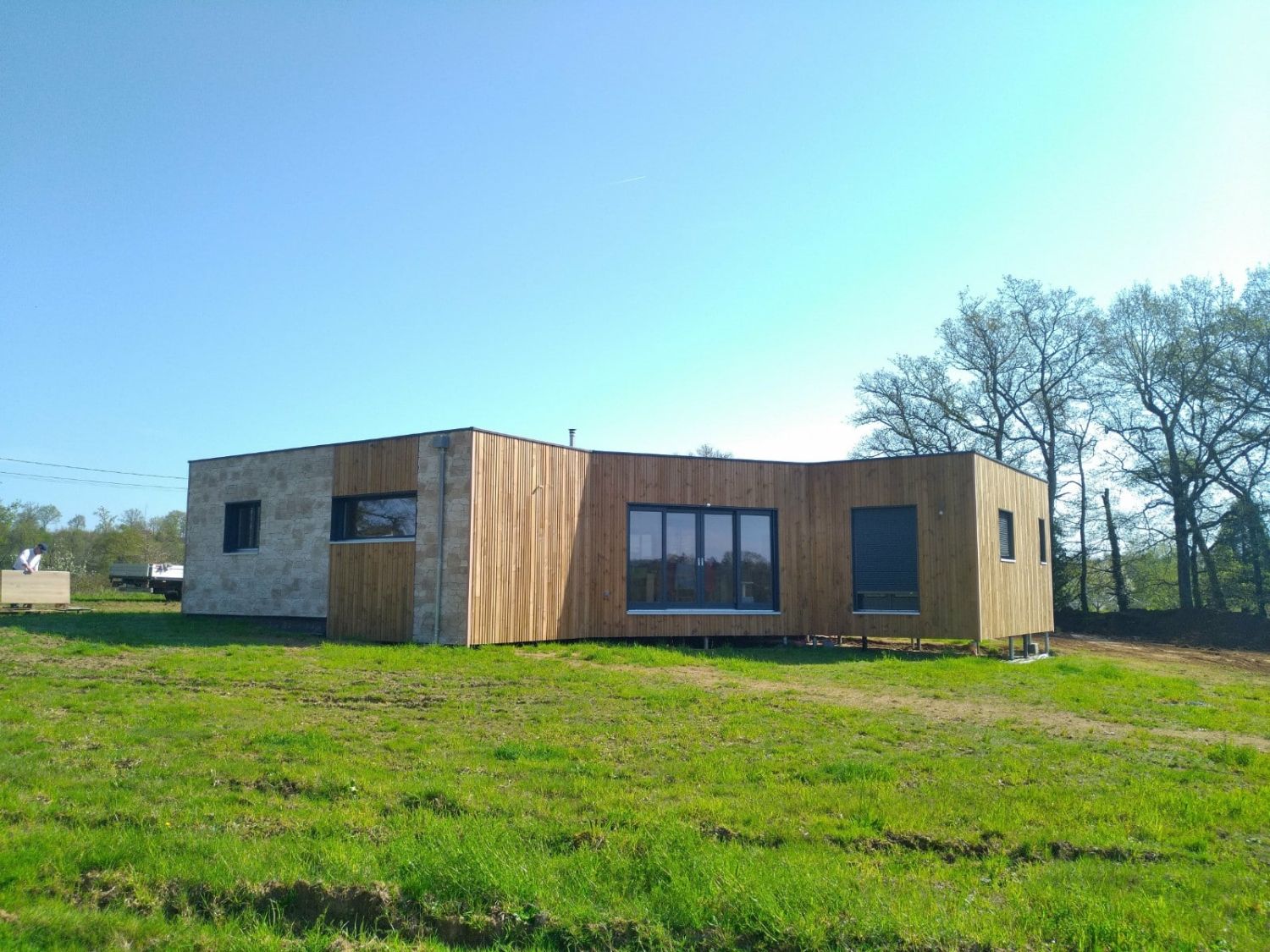 Maison à ossature bois bardée de bois, posée dans un pré